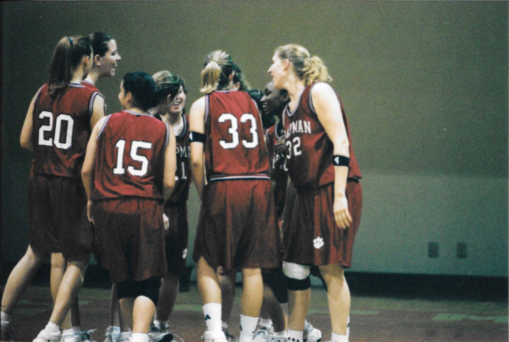 Ten women on the Chapman University women's basketball team gather into a huddle.